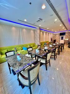 Zenith Smart Vacation Homes, Ajman في عجمان: مطعم بطاولات وكراسي وأريكة خضراء