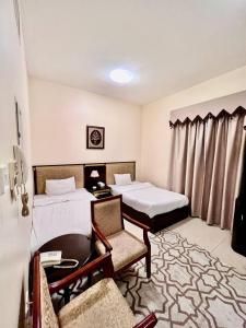 a hotel room with two beds and a table and chairs at Zenith Smart Vacation Homes, Ajman in Ajman 