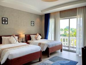a hotel room with two beds and a window at Sokchea Kampot Hotel in Kampot