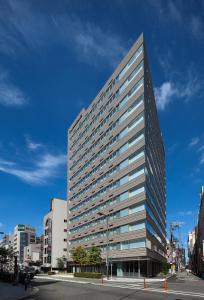 ein hohes Gebäude mit Fenstern auf einer Stadtstraße in der Unterkunft Fraser Residence Nankai Osaka in Osaka