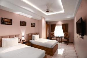 una camera d'albergo con due letti e una televisione di Pearl Inn Hotel a Karachi