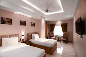 a hotel room with two beds and a television at Pearl Inn Hotel in Karachi