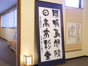 a framed picture of asian characters on a wall at 信州安曇野穂高温泉郷　旅館　山のたこ平 in Azumino