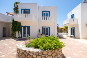 a large white building with blue windows and a courtyard at Alexis Apartments in Stavros