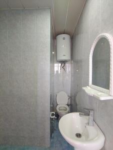 een badkamer met een wastafel, een toilet en een spiegel bij Lahore Hotel Baku in Baku