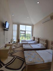 a room with four beds and a flat screen tv at Lahore Hotel Baku in Baku