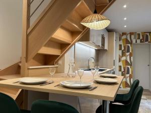 a kitchen with a wooden table with plates and wine glasses at Maison avec cour intérieure in Souillac