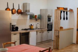 a kitchen with wooden cabinets and a stove top oven at Chambres d'hôtes - Le Mas du Colombeyras in Espeluche