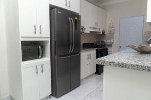 a kitchen with a black refrigerator and white cabinets at Cozy Beach House in La Romana