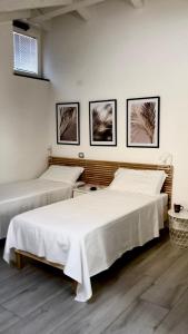 two beds in a room with three pictures on the wall at The sweet attic room - De Vivo Realty Meta di Sorrento in Meta