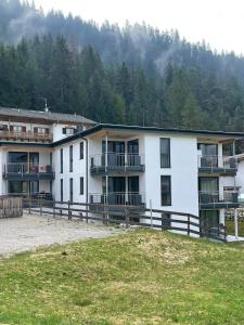 a large white building with balconies and a field at Appartements Luxner in Achenkirch