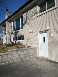 a house with a white door and a brick wall at Entire Basement Apartment in Mississauga, Etobicoke in Mississauga