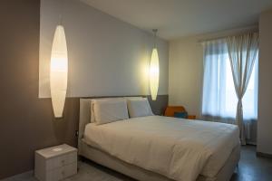 una camera da letto con un letto con lenzuola bianche e due luci di Gomes Comfort House 2 a Valeggio sul Mincio
