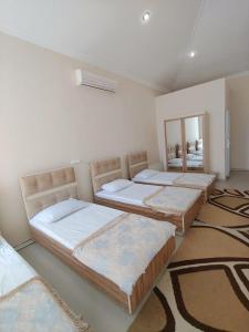 three beds in a room with rugs at Lahore Hotel Baku in Baku