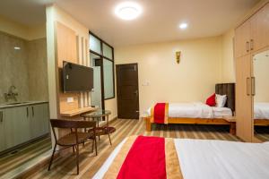 a hotel room with two beds and a tv at Hotel Atithi Satkar in Nagarkot