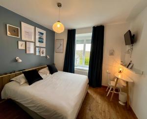 a bedroom with a white bed and a window at Hôtel Restaurant La Maison in Trébeurden