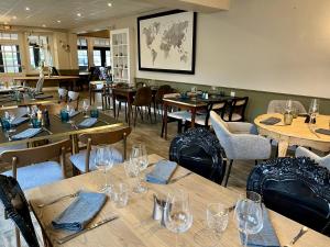 un restaurante con mesas de madera y sillas con copas de vino en Hôtel Restaurant La Maison, en Trébeurden