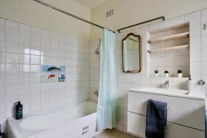 un bagno bianco con vasca e lavandino di Affordable 2 Bedroom House Surry Hills 2 E-Bikes Included a Sydney