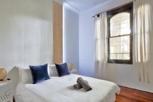 una camera da letto con un letto bianco con cuscini blu e una finestra di Affordable 2 Bedroom House Surry Hills 2 E-Bikes Included a Sydney