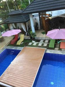 a swimming pool with umbrellas and chairs next to a house at Forest green resort in Lipa