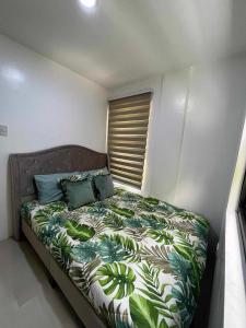 a bedroom with a bed with a green and white comforter at Forest green resort in Lipa