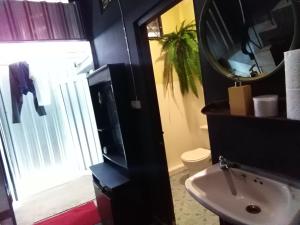 ein Badezimmer mit einem Waschbecken, einem Spiegel und einem WC in der Unterkunft Goodnighthostel@Trang in Trang