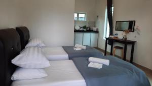 a room with two beds with pillows and a table at D'LaMar Homestay in Pendang
