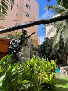 a woman in a dress sitting on a pole in a garden at Atlantis Condominium Resort Pattaya in Jomtien Beach