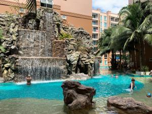 a pool at a resort with people in the water at Atlantis Condominium Resort Pattaya in Jomtien Beach