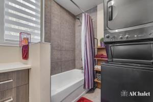een kleine badkamer met een bad en een douche bij L'Artiste - Chic conco avec piscine in Wendake
