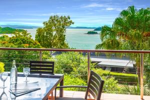 Haven on Hamilton Island -private apartment with views & buggy Fully Renovated in 2023 في جزيرة هاميلتون: طاولة وكراسي على شرفة مطلة على المحيط