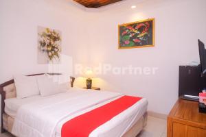 Un dormitorio con una cama y un televisor. en Ndalem Pundhi Maguwoharjo RedPartner, en Seturan