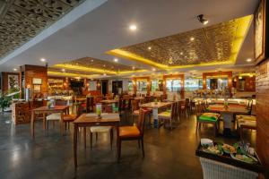 a restaurant with tables and chairs and a bar at Metland Seva Seminyak - Formerly Horison Ultima Seminyak in Seminyak