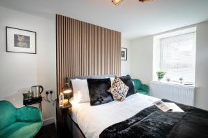a bedroom with a bed and two green chairs at Kings Arms Suites - Luxury Double - Freestanding Bath - Self Check In in Whitehaven
