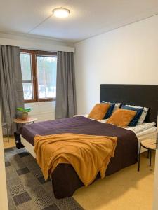 a bedroom with a large bed and two windows at Tilava 2BR-huoneisto Saunalla in Oulu