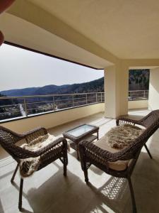 a balcony with two wicker chairs and a table at Royal Trip Luxury Apartment Sinaia in Sinaia