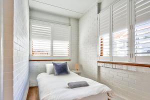 a small bedroom with a bed and two windows at Spacious 3 Bedroom on the edge of Downtown Herford St 2 E-Bikes Included in Sydney