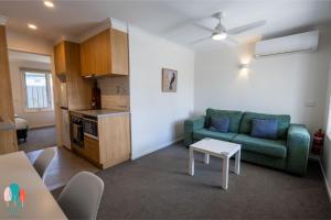 a living room with a green couch and a table at Botanic City Apartments in Warrnambool