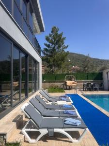 a row of lounge chairs next to a swimming pool at Villa nightblue in Ortaca