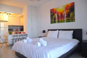 a bedroom with a large white bed and a kitchen at Varkiza Riviera Studio by the Sea in Varkiza