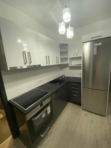 eine Küche mit weißen Schränken und einem Kühlschrank aus Edelstahl in der Unterkunft Kossuth 41 in Balatonlelle