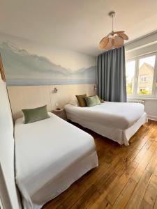 two beds in a hotel room with a window at Hôtel Restaurant La Maison in Trébeurden