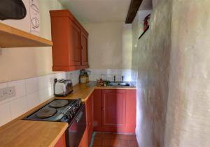 a small kitchen with red cabinets and a stove at The Gatehouse in Llanrwst