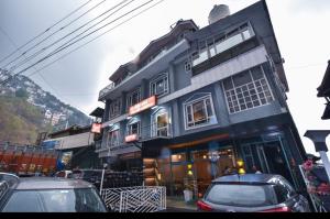 西姆拉Hotel Avalanche的一座蓝色的建筑,前面有汽车停放