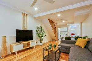 a living room with a couch and a flat screen tv at Vibrant 3 Bedroom House Darlinghurst 2 E-Bikes Included in Sydney