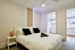 a bedroom with a large white bed with black pillows at Vibrant 3 Bedroom House Darlinghurst 2 E-Bikes Included in Sydney
