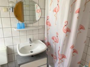 a bathroom with a sink and a shower curtain with pink flamingos at Kölp - Hengstler in Kolpinsee