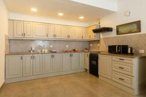 a kitchen with white cabinets and a black stove at Aguada Anchorage - The Villa Resort, Candolim in Candolim