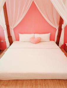 Dormitorio rosa con cama blanca y almohada cardiaca en 墾丁巴里小城堡, en Hengchun