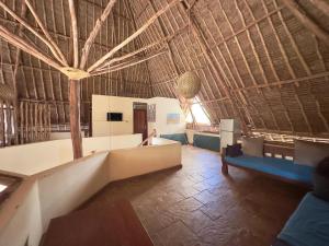 a living room with a straw roof with a couch and chairs at Villa Twiga in Ukunda